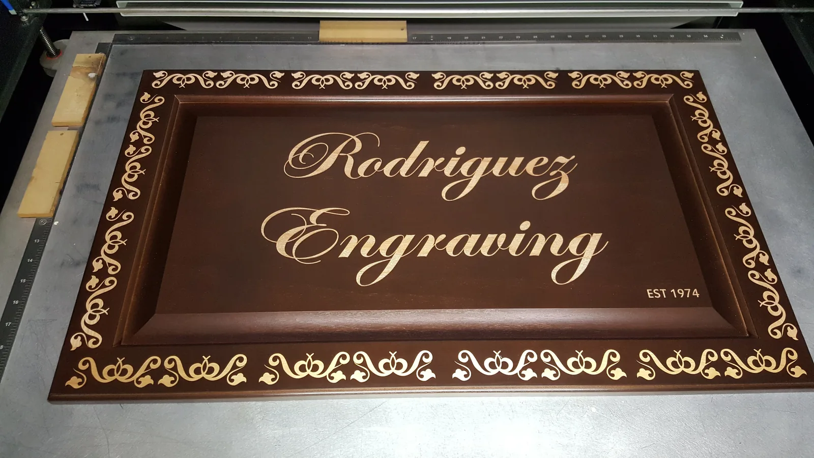 Engraved wooden Rodriguez Engraving sign reading Est 1974 on the laser engraver bed