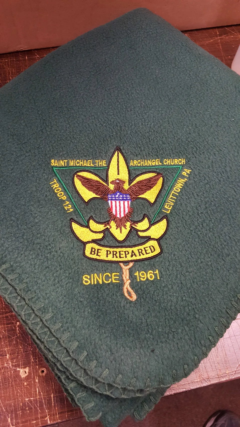 Green fleece blanket embroidered with a Scout troop crest and lettering